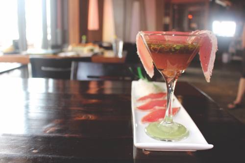 Tuna is plated next to a glass with pieces draped in a spicy ponzu sauce.