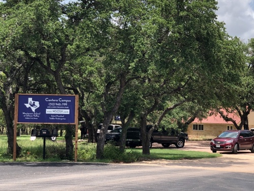 A blue sign in front of a school
