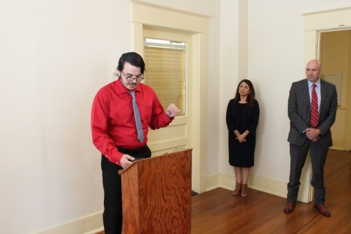 Eric Martinez, policy director with Mano Amiga, speaks alongside Hays County commissioners Debbie Ingalsbe and Lon Shell at the Hays County Courthouse on April 12. (Eric Weilbacher/Community Impact Newspaper)