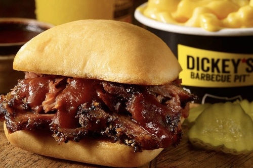 Barbecue sandwich with pickles next to a DIckey's Barbecue Pit cup