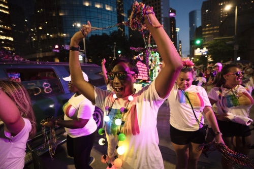 person walks at the Pride Houston event with rainbow lights, beads