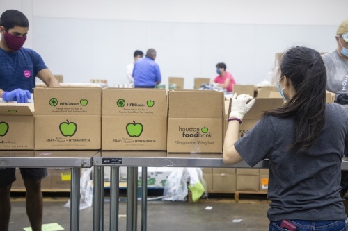 Volunteers with the Houston Food Bank help pack boxes along an assembly line. (Courtesy Houston Food Bank)