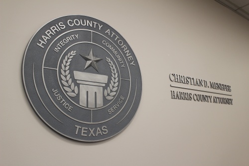Gray seal of county attorney with a star over a column, along with the attorney's name. 