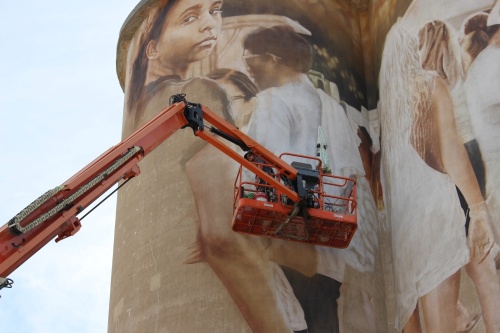 Artist Guido van Helten works on the McKinney Silo Mural Project on Aug. 15. (Colby Farr/Community Impact Newspaper)
