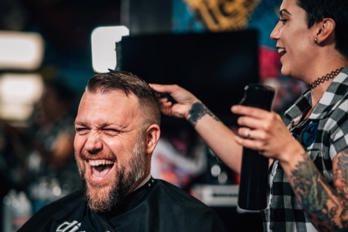 man laughing while getting hair trimmed