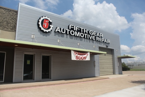 Storefront of Fifth Gear Automotive Repair with large name sign and hanging 'coming soon' sign underneath.