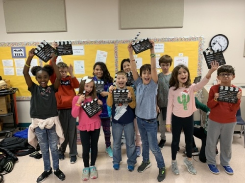 A photo of kids smiling and holding director's cut props.