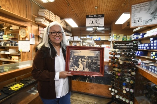 




Owner Edie Almogabar poses with a photo of Village Shoe Shop from its first year of operation in 1947. (Photos by Hunter Marrow/Community Impact Newspaper)