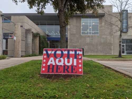 A photo of a sign that reads "Vote Here" and "Vote Aqui"
