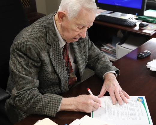 Mayor Tom Reid at a desk signing an official document