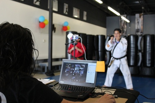 Co-owner and instructor Paul Resurreccion leads a virtual martial arts lesson online, while his wife, Hazel, manages the chat room. (Adriana Rezal/Community Impact Newspaper)