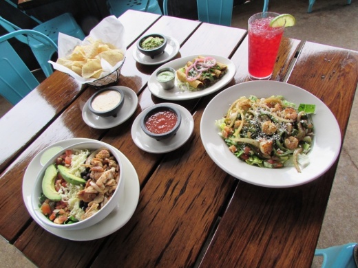 A table setting includes a Powerbowl; a Skinny Maida’s Salad; Flautitas De Pollo; and chips with salsa, queso and guacamole. (Nicholas Cicale/Community Impact Newspaper)