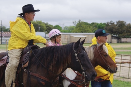 David Wiedenfeld and his granddaughter sit atop their horses while talking to Wiedenfeld's son-in-law, Wade Zaeske. (Warren Brown/Community Impact News)