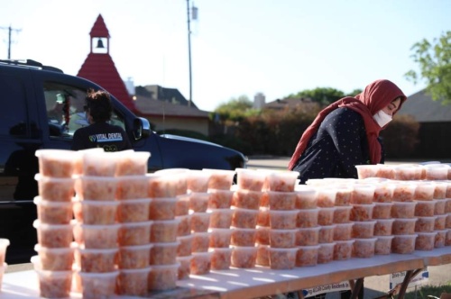 Noreen Choudhury, a volunteer with In-Fretta, gathers meals for a family outside of Allen Community Outreach. (Liesbeth Powers/Community Impact Newspaper)