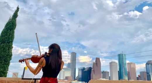 Violinist Mayu Greenhalgh performs from artist Allan Rodewald’s rooftop patio at a drive-by art exhibit held in First Ward. (Courtesy Amber Slaughter)