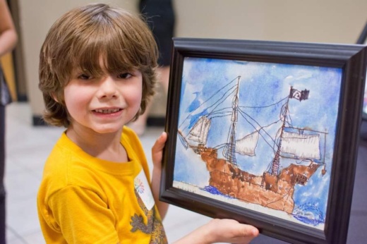 A photo of a young boy holding a painting of a ship