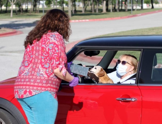 District nurse Cristin Wicketts hands a gift box to Knowles Elementary School nurse Julie Davis—and her dog Daisy—on May 6 at Vista Ridge High School in Cedar Park. (Courtesy Leander ISD)