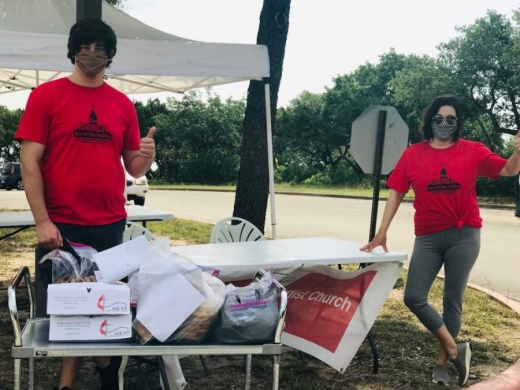 A photo of two people wearing masks and red Oak Hill UMC shirts while distributing cookies