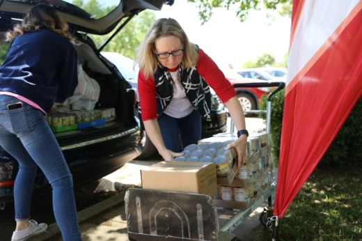 Mimi Conner (right) unloads food from her car after picking up nonperishable foods from the North Texas Food Bank and purchasing foods from Aldi, with help from volunteer Michelle Leavitt. (Liesbeth Powers/Community Impact Newspaper)