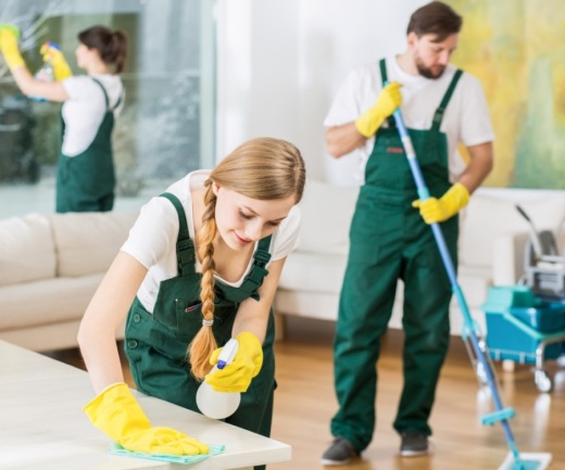 A photo of three people cleaning a living room