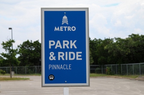 A photo of a blue sign in a parking lot that reads "Park & Ride Pinnacle"