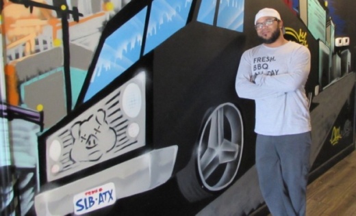SLAB BBQ & Beer co-owner Raf Robinson stands in front of a mural at the restaurant's Southwest Austin location in 2019. (Nicholas Cicale/Community Impact Newspaper)
