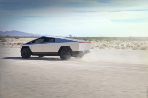 A photo of a silver Cybertruck zooming through the desert