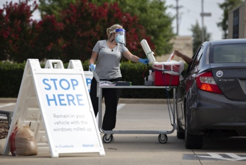 Pharmacist Emily Smith opens a cooler for a patient to place their self-swab coronavirus test at a Walmart drive-thru testing site in McKinney on June 29. (Shelby Tauber/The Texas Tribune)