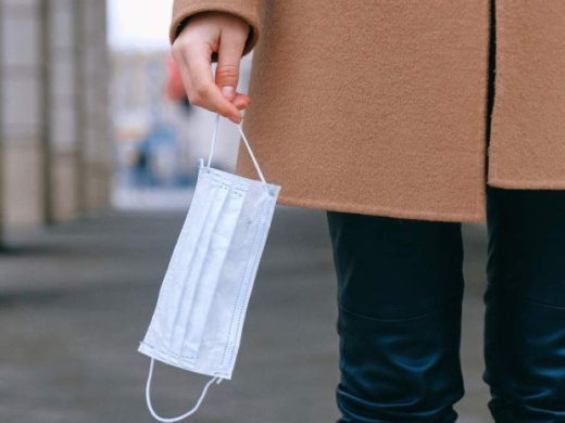 A photo of a woman's hand holding a disposable mask
