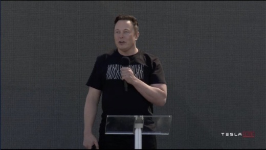 A screen shot of Elon Musk speaking into a microphone