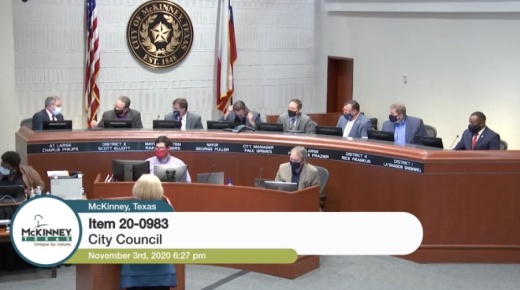 On the far left of the dais, Charlie Phillips goes in to fist-bump fellow Council Member Scott Elliot after council approved a resolution to hire an architect to design the city's new municipal complex. (Screenshot by Miranda Jaimes/Community Impact Newspaper)