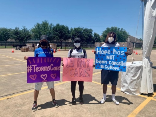 Cy-Hope volunteers hold up encouraging signs during a food distribution event with the Houston Food Bank on May 6. (Courtesy Cy-Hope)