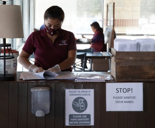 A hostess at Maple Bacon folds single-use menus ahead of the arrival of customers. (Liesbeth Powers/Community Impact Newspaper) 