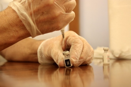 Photo of a vaccine vial being emptied into a needle