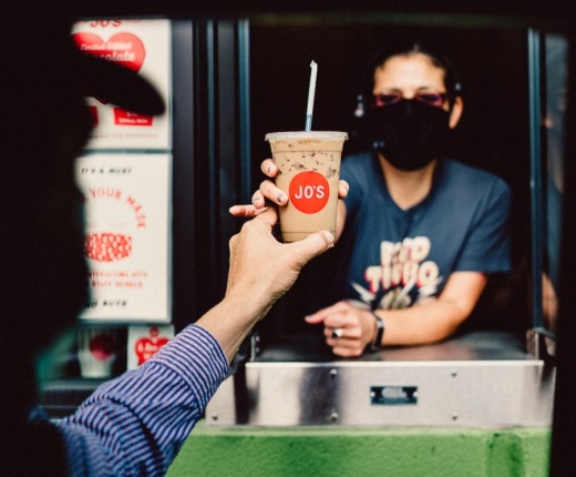 Photo of a Joe's coffee barista handing off a drive-thru coffee