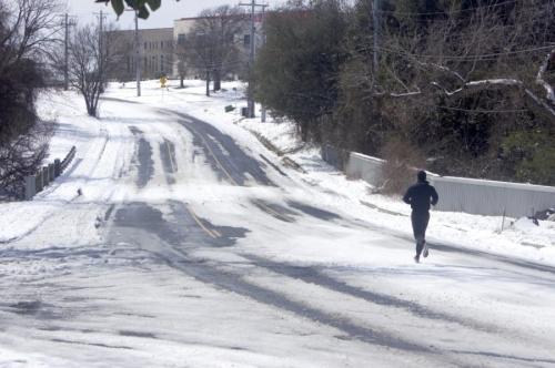 A lone runner jogs on a snow-covered road in Austin. Transportation projects across the city were briefly paused due to Winter Storm Uri. (Jack Flagler/Community Impact Newspaper)