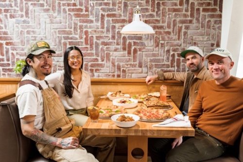 Photo of four people in a booth with pizza