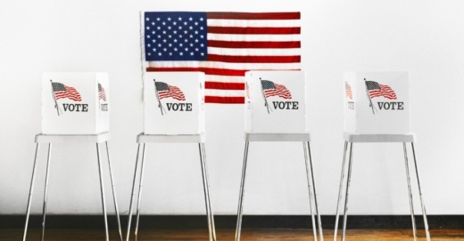 Photo of a series of "vote" signs with an American flag