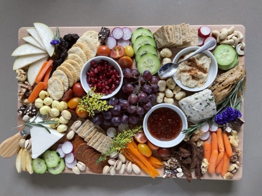 A charcuterie board featuring fruits, vegetables, crackers and cheese