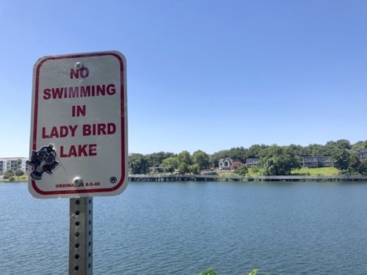 A sign along the Ann and Roy Butler Hike and Bike trail reminds residents not to swim in Lady Bird Lake. (Jack Flagler/Community Impact Newspaper)