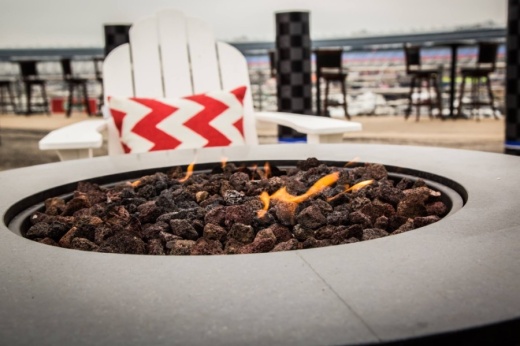 A lit patio fire with a lounge chair overlooking Texas Motor Speedway