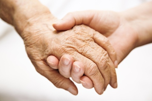A young person and an old person holding hands
