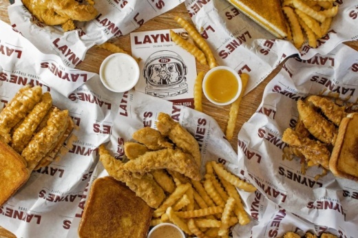 Baskets of chicken fingers, fries, bread and sauces around a Layne's flyer
