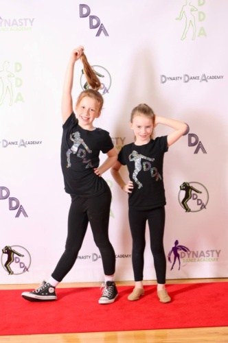 Two young dancers pose before a backdrop at the Dynasty Dance Academy Social.