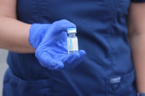 Photo of a gloved hand holding a vaccine vial