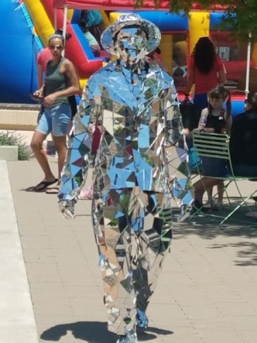 A man covered in mirrors walks towards the viewer. 