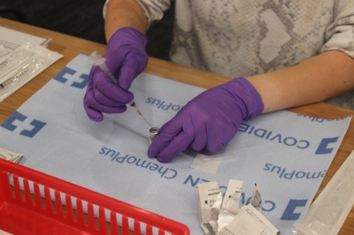 Photo of hands in purple gloves prepared a vaccine vial