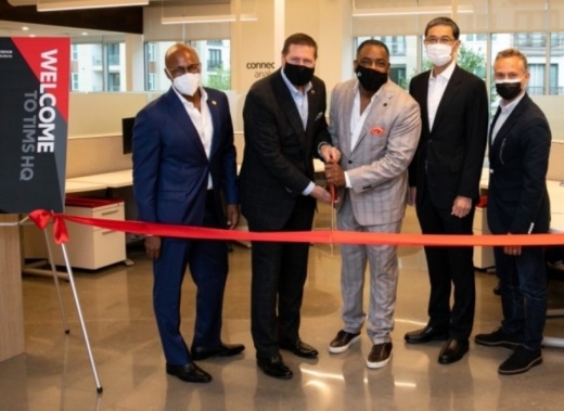 Five men in an office cutting a ribbon