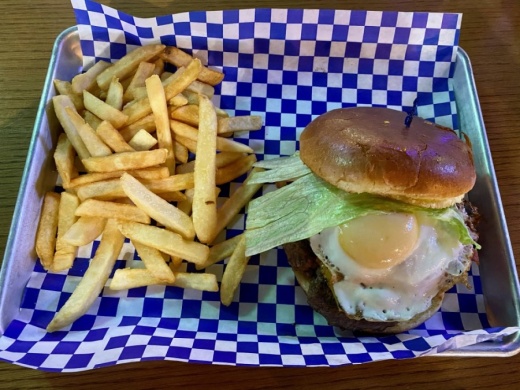 Old Town Burger ($10.95) includes a beef patty with caramelized onions, bacon, cheese, lettuce and tomatoes and topped with a fried egg on a brioche bun and a side of fries. (Yvonne Brown/Community Impact Newspaper)