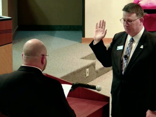 Dan Jaworski with his hand up while he is being sworn in.
